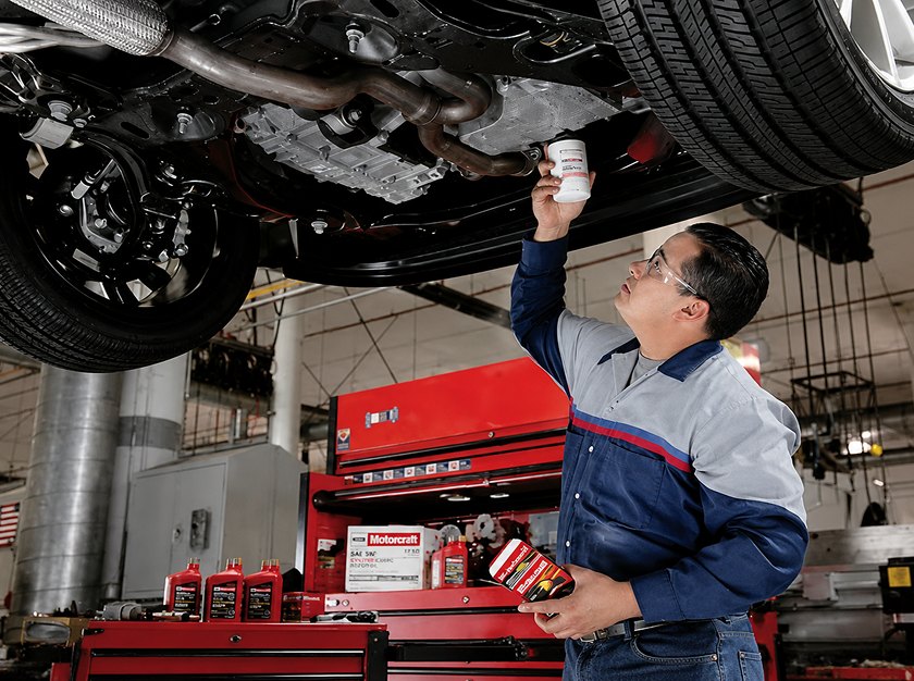 Technician inspecting the underside of a vehicle