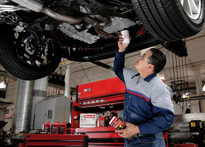 Technician inspecting the underside of a vehicle